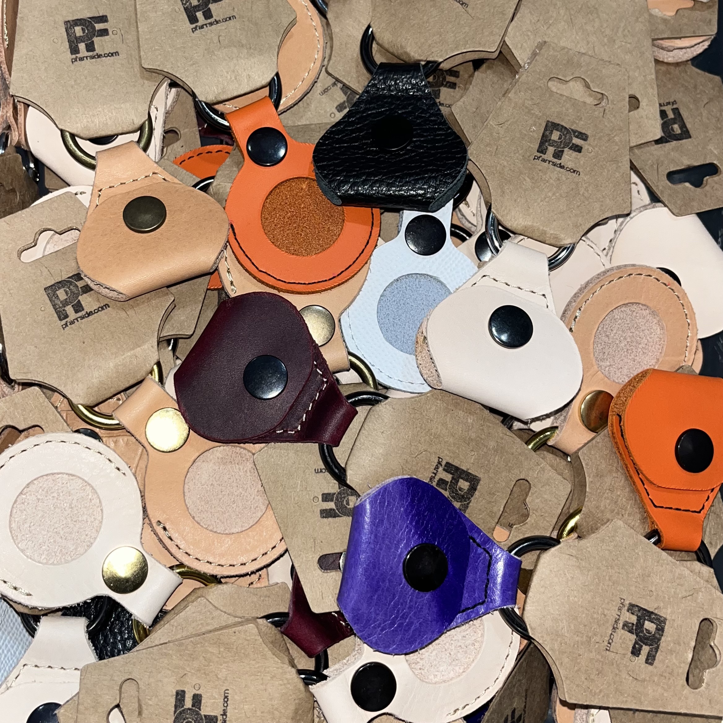 A pile of leather guitar pick holders and apple tag holder.