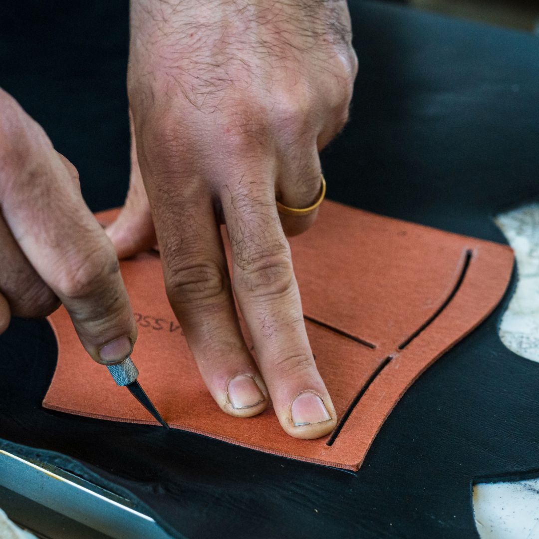 A close up of a person's hand beveling a piece of leather.